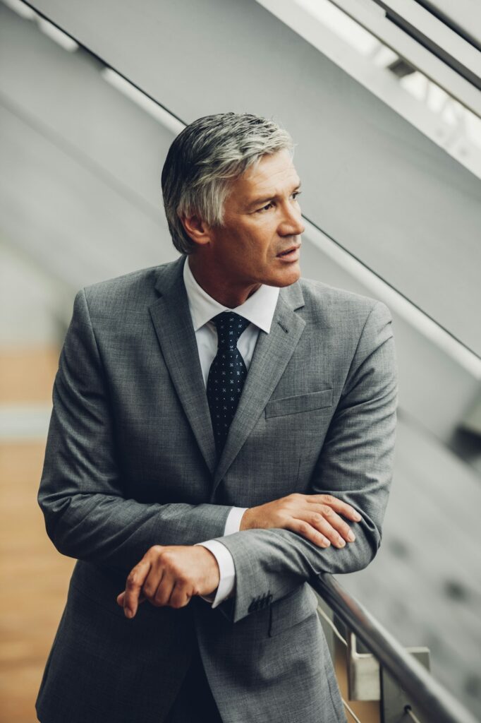 Mature businessman standing by railing looking away