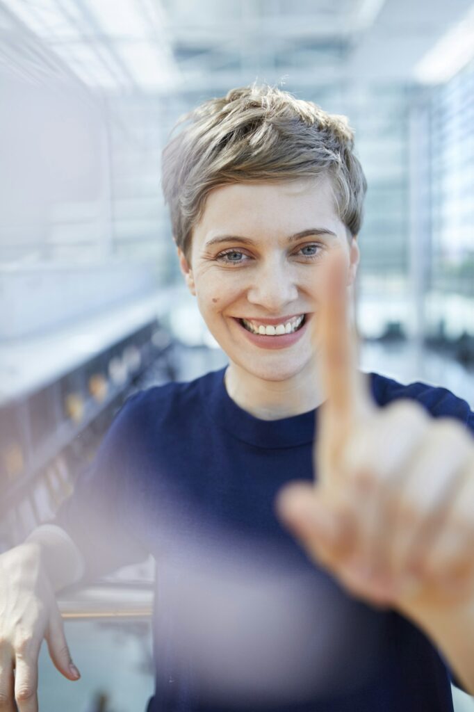 Portrait of blond businesswoman touching at glass pane