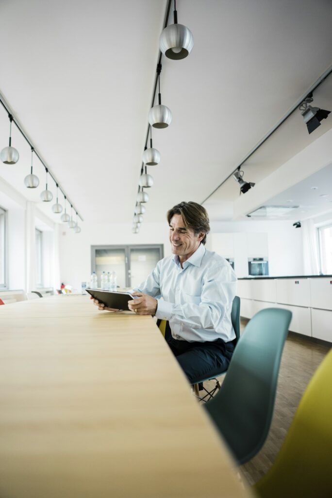 Smiling businessman using tablet at table in office